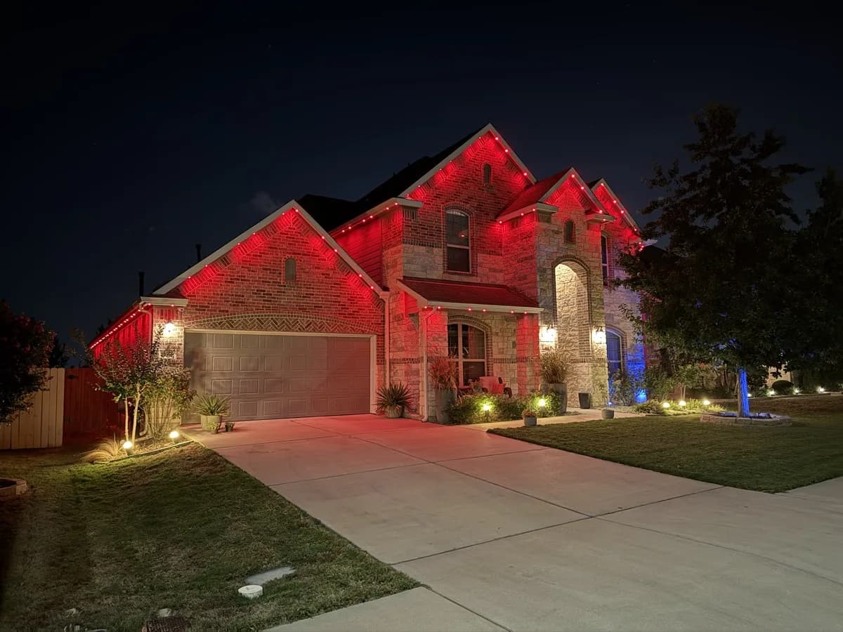 Red roofline lights above the garage and second story of an Austin brick home.