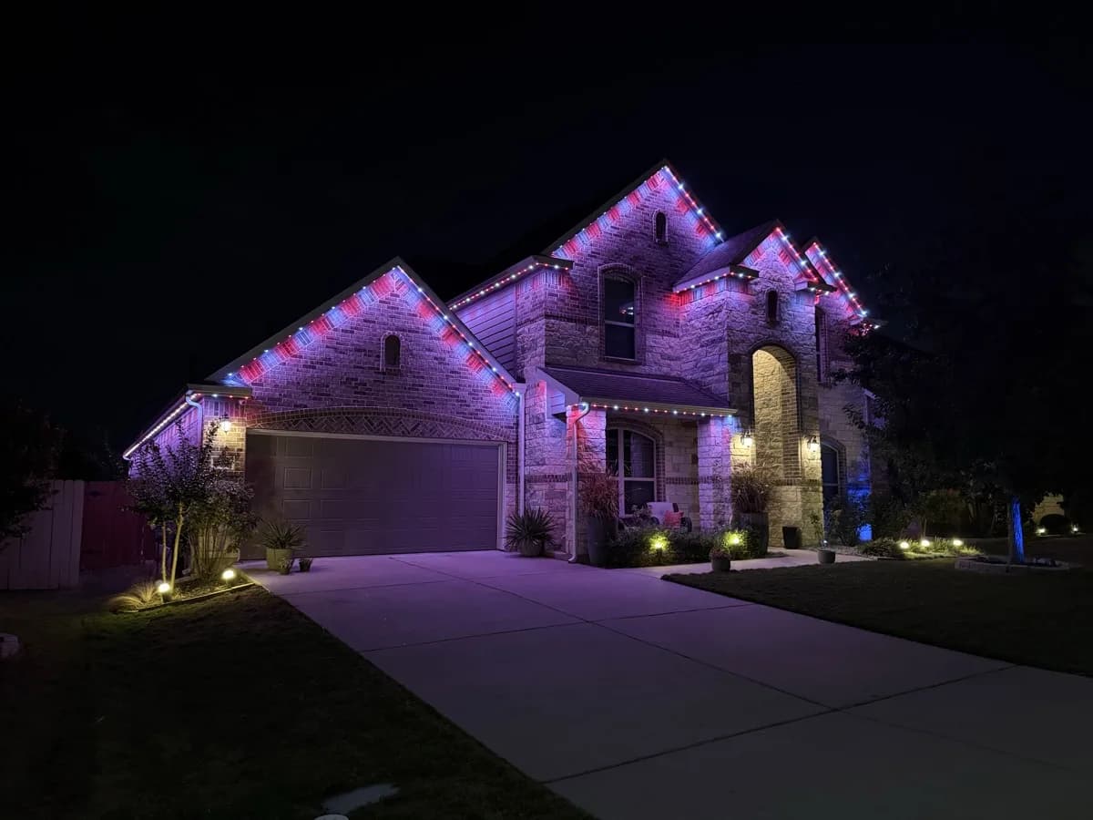 Purple, red, and white lighting across the roofline of the same Austin home.
