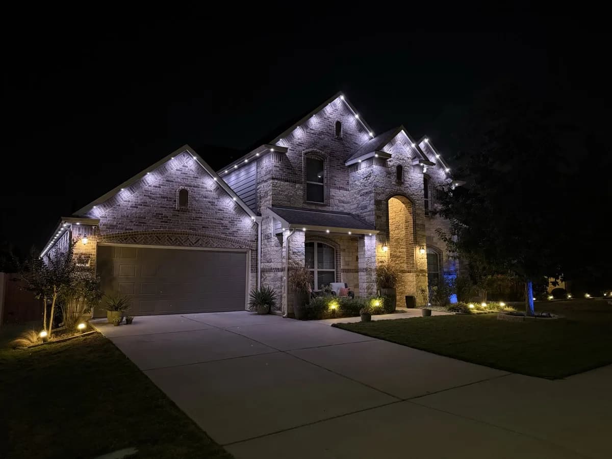 White roofline lights trace the peaks and garage of a two-story brick home in Austin.