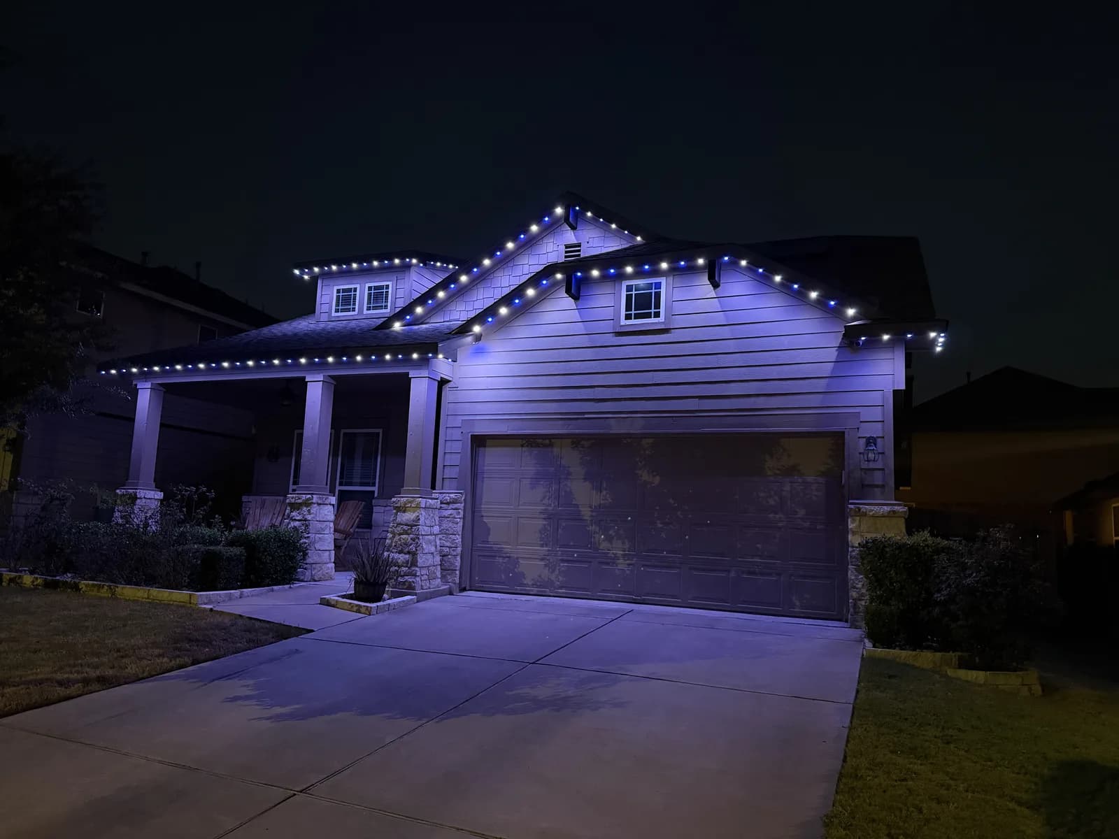 Blue and white lights illuminate the gables and porch of a Pflugerville home.