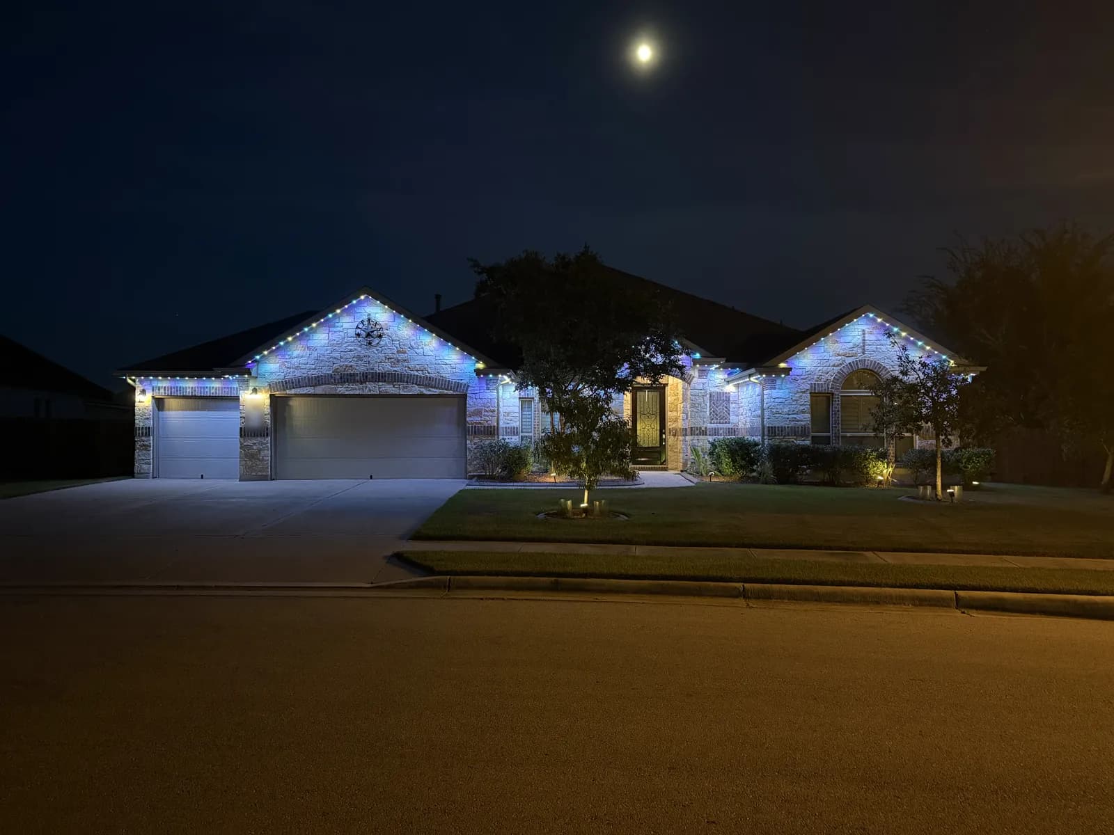 Blue and white roofline lights on the same single-story Pflugerville home.