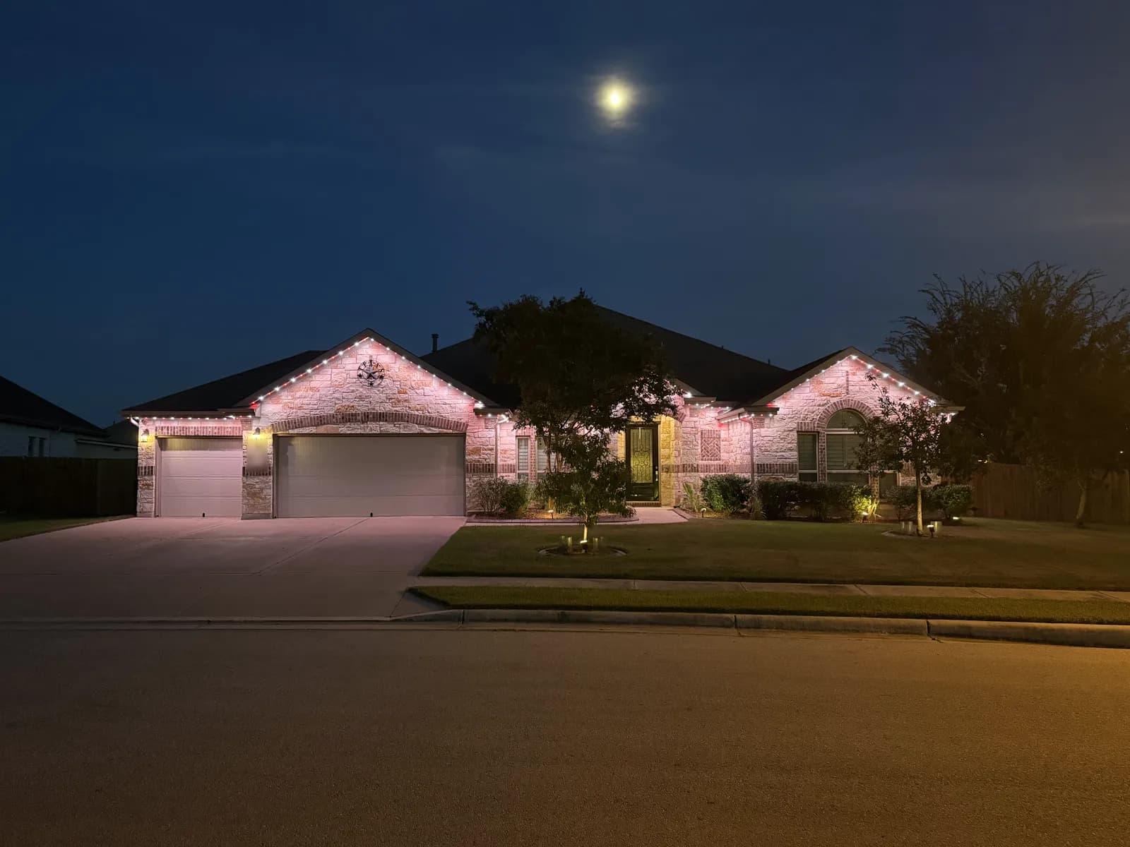 Pink roofline lights on the same single-story Pflugerville home.