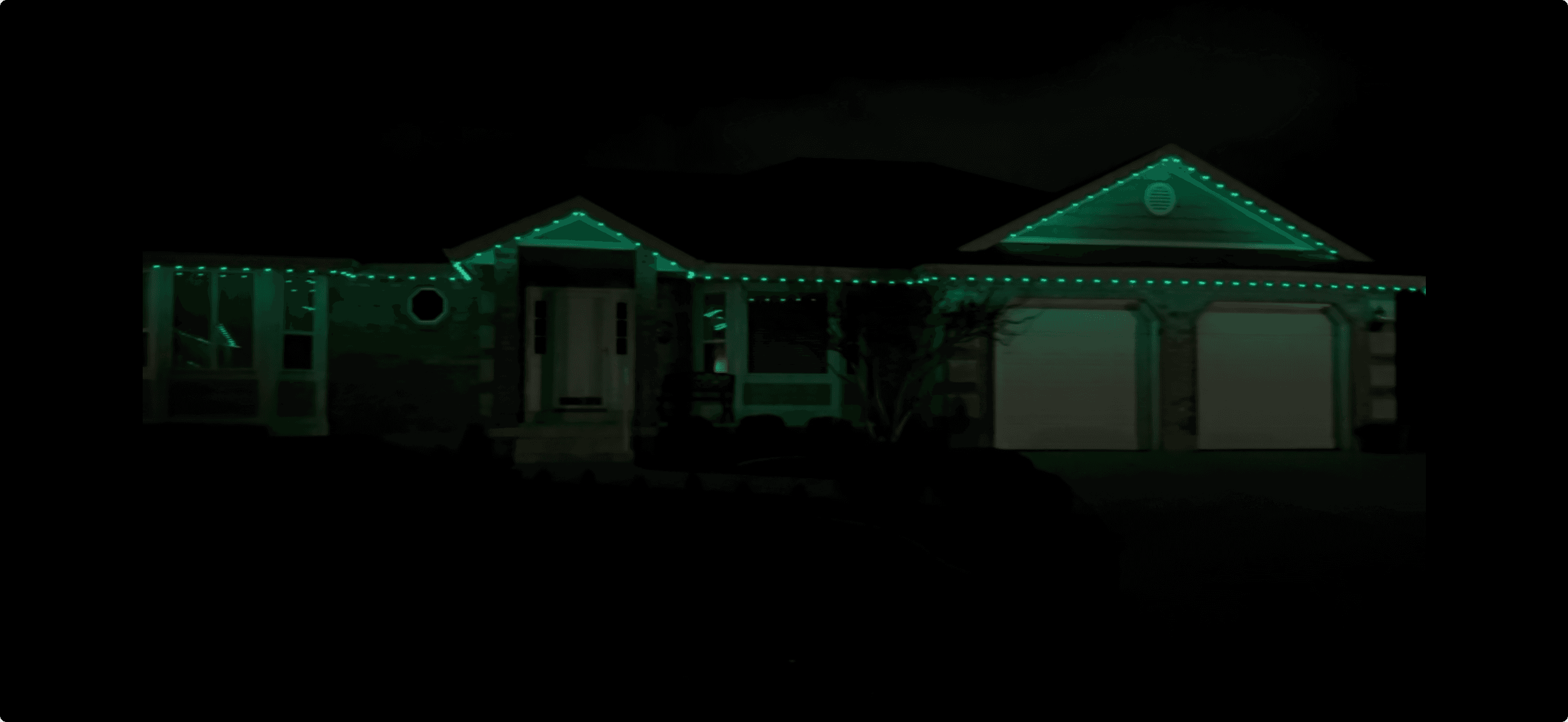 Home at night with green Trimlight lights tracing its roofline and gables