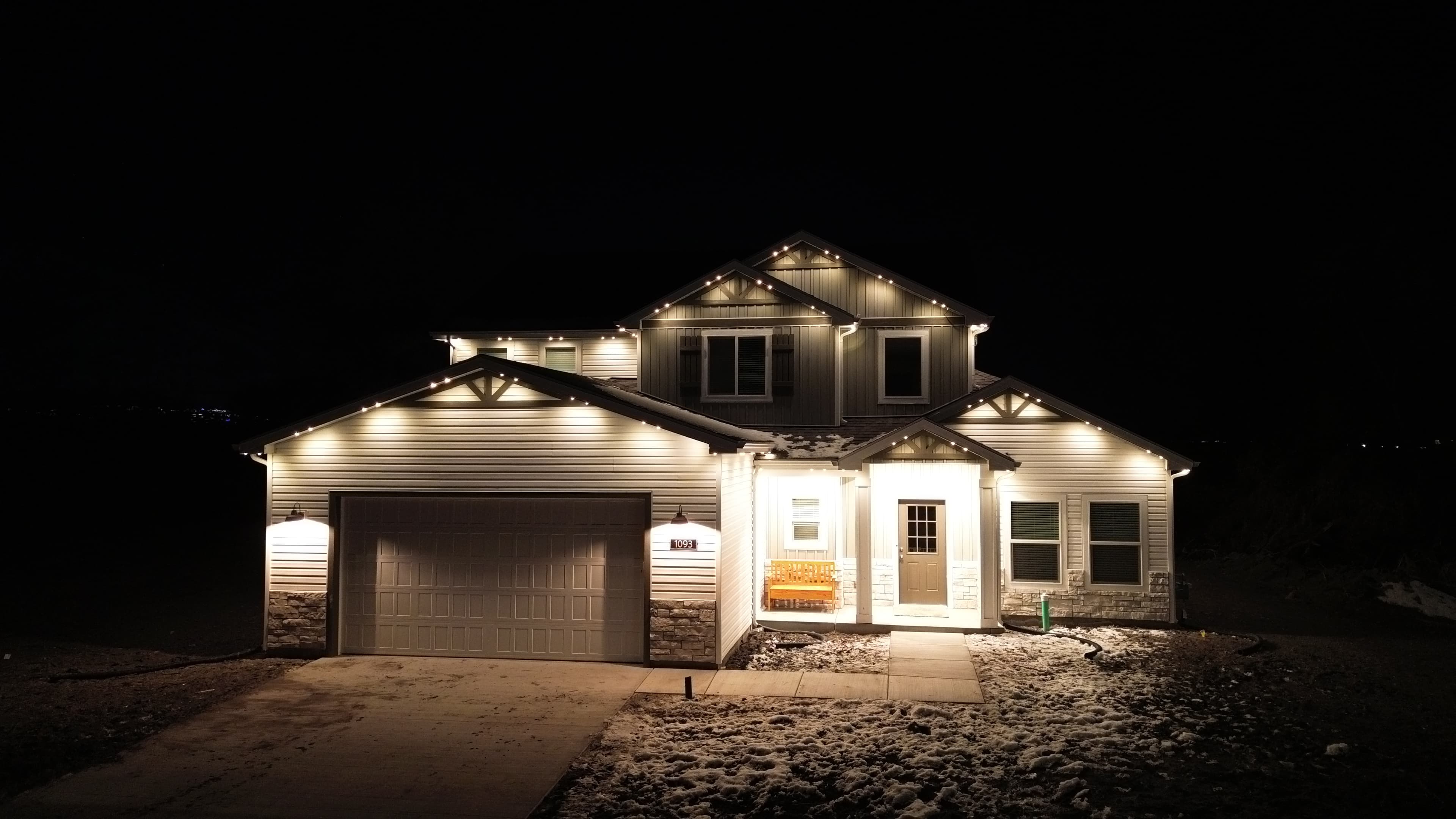 Warm white permanent LED roofline lighting on a wooded Garden Ridge acreage home