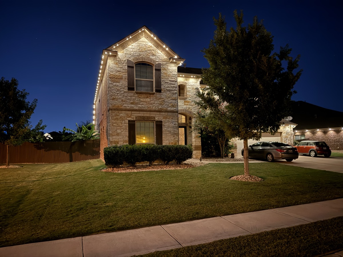 Professional permanent lighting installation on an Austin stone home at dusk