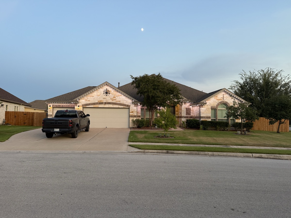 App-controlled permanent LED lighting on a limestone Austin home at night